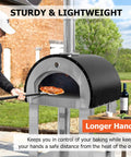 Pizza oven in backyard, stainless steel body with a long-handled pizza peel sliding a pizza inside.