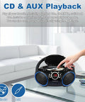 Hand operating Portable CD Player Boombox With Top-Loading Disc, 20-Track Programmable Memory, AM/FM Stereo, in modern living room.