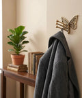 Knockout Brass Butterfly Swivel Hook Foldable Tri Arm Gold Finish Coat Rack holds gray coat on wall, space-savvy closet organizer.