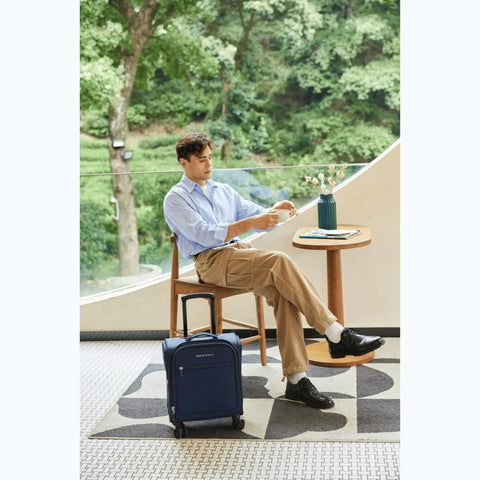 Man sitting with 14 Inch Underseat Carry On Luggage With Spinner Wheels And USB Charging Port on a cafe patio.