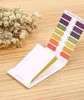 Open pack of PH Test Strips 0-14, 80 Count Litmus Paper for Saliva Urine Water Soil Testing with Color Chart on wood table with dried flowers