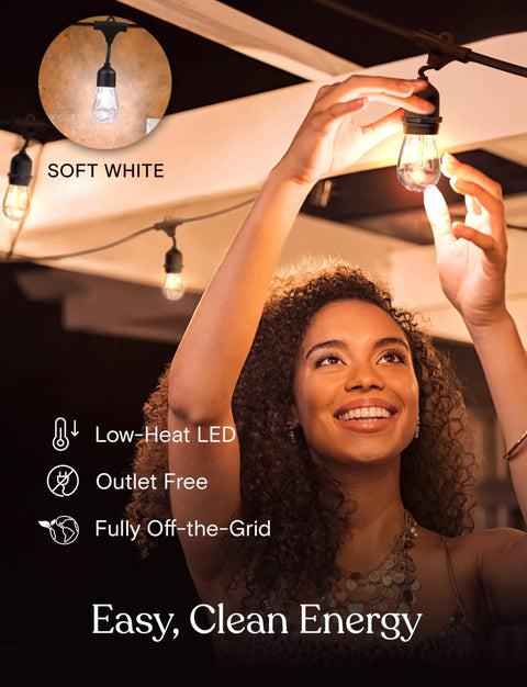 Woman installing Ambience Pro Solar Powered Outdoor String Lights with remote control and Edison bulbs under patio roof.