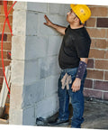 Man wearing Heavy Duty Cut Resistant Wrist Sleeves For Men And Women Beefy Arm Guards while working on a wall.