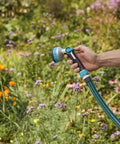 Heavy Duty Thumb Control Garden Hose Nozzle With Eight Pre Set Spray Patterns in hand watering colorful flowers outdoors