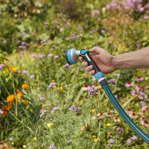 Heavy Duty Thumb Control Garden Hose Nozzle With Eight Pre Set Spray Patterns in hand watering colorful flowers outdoors