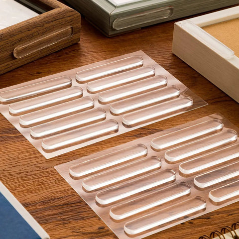 Clear Stick-On Cabinet Door Bumpers Pack Of 40 on a wooden table, showing silicone strips for quiet closings, 2.75x0.4 inches.