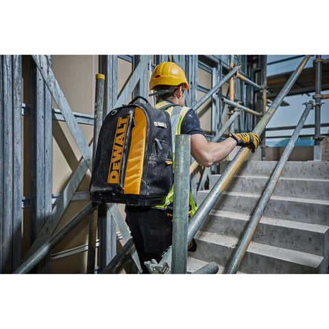 Man carrying a Massive 40 Liter Tool Backpack Built Tough As Nails For Contractors up construction stairs.