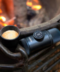 Nanopresso Portable Espresso Maker With 18 Bar Pressure Manual Battery Free Travel Coffee Kit For Rich Crema On The Go Evolution From Minipresso Compact Grey next to espresso cup by campfire
