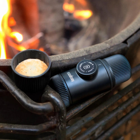 Nanopresso Portable Espresso Maker With 18 Bar Pressure Manual Battery Free Travel Coffee Kit For Rich Crema On The Go Evolution From Minipresso Compact Grey next to espresso cup by campfire