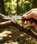 Person using Stainless Steel Foldable Knife With Wood Handle And Locking Blade For Hiking And Camping Ultra Portable And Easy To Carry Outdoors