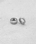 Close-up of two metal rings from Presta Valve Core Lock Ring Nuts Set 10 Pack Durable Metal Lock Rings For Presta Valves And Bicycle Inner Tubes Rust Resistant 5mm Inner Diameter 10mm Outer Fits Air Pumps And Compressors on textured surface
