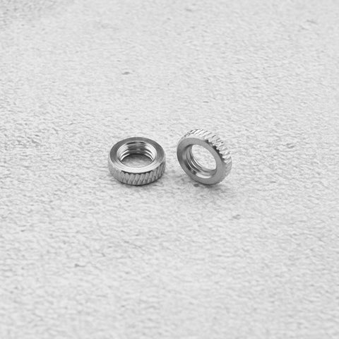 Close-up of two metal rings from Presta Valve Core Lock Ring Nuts Set 10 Pack Durable Metal Lock Rings For Presta Valves And Bicycle Inner Tubes Rust Resistant 5mm Inner Diameter 10mm Outer Fits Air Pumps And Compressors on textured surface