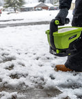 Person using 20-Volt Cordless Handheld Seed And Fertilizer Spreader For Yard Work With Adjustable Spreading Rate Dial on snowy path