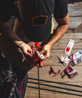 Man using Pro Class Fletching Jig for 5.5in vanes and feathers, positioned on table with tools, displaying magnetic clamp and precise offset