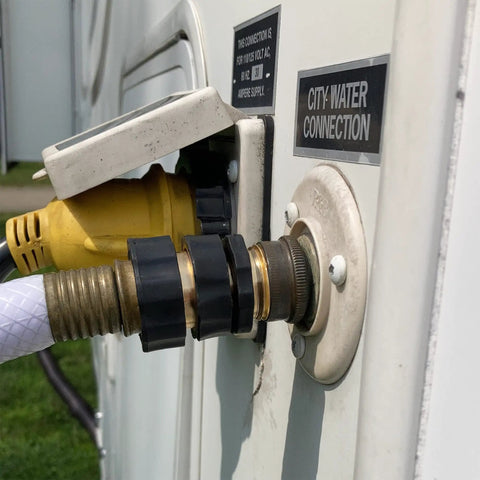 RV city water connection showing a hose attached to a metal fitting on a white vehicle side panel, labeled 'City Water Connection'.
