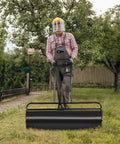 Person using heavy duty lawn roller water or sand filled steel drum roller with U shaped handle for yard work, 24x13 inch, 13 gallon.