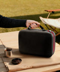 Slick Waterproof Coffee Grinder Travel Case Hella Rugged Shockproof Portable Storage Pouch held with a grab handle on a table.