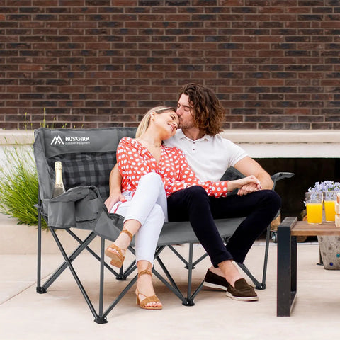 Couple sitting on Two Person Padded Camping Chair For Outdoor Lounging, Gray – Heavy Duty Oversized Camping Loveseat With Cup Holders