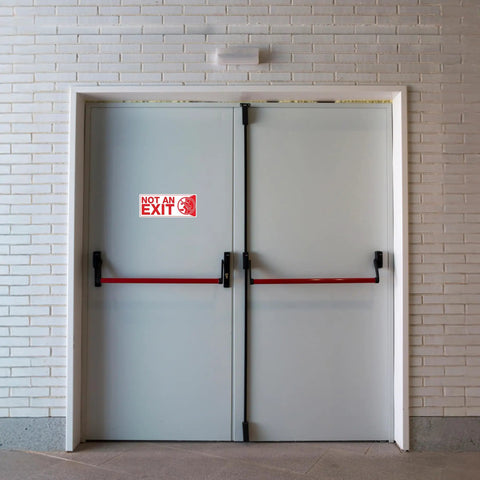 Not an Exit Sign Sticker Pack, 6 Pack, 10 By 4 Inch Self Adhesive Vinyl Decals on gray double doors in a hallway