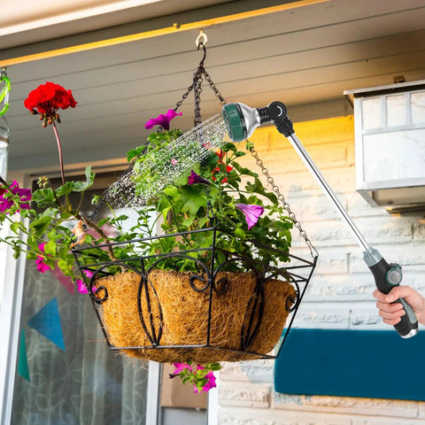 Person using 24 Inch Garden Hose Watering Wand With 8 Spray Patterns to water hanging basket of flowers on patio