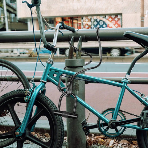 Blue bike secured with 12Mm Thick Heavy Duty Bike Lock Cable With Vinyl Coating And Loops Braided Steel Security Cable, street setting.
