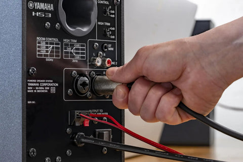 Hand connecting cable to HS4 Black Powered Studio Monitors Pair With 4.5 Inch Woofer And 1 Inch Dome Tweeter 60 Hz To 22 kHz 26W