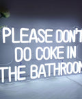 White neon sign on acrylic reads "Please Don't Do Coke In The Bathroom"