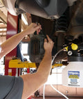 Mechanic using Pro Grade Hydraulic Brake And Clutch Bleeding Kit For Cars, Trucks, SUVs And Motorcycles with air-operated reservoir