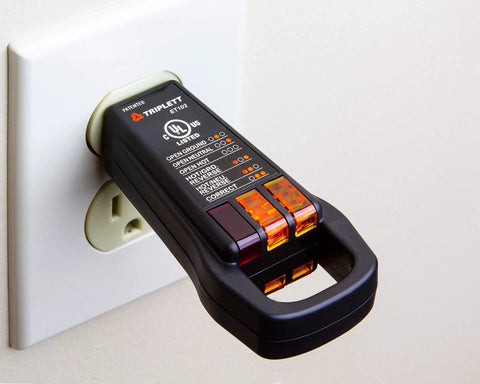 ET102 3-Wire Outlet Tester with Finger Loop plugged into a white wall outlet, black plastic receptacle tester