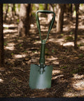 Ready For Anything 23 Inch Military Foldable Camping Shovel With Cover in Mn Steel, standing open in a forest setting