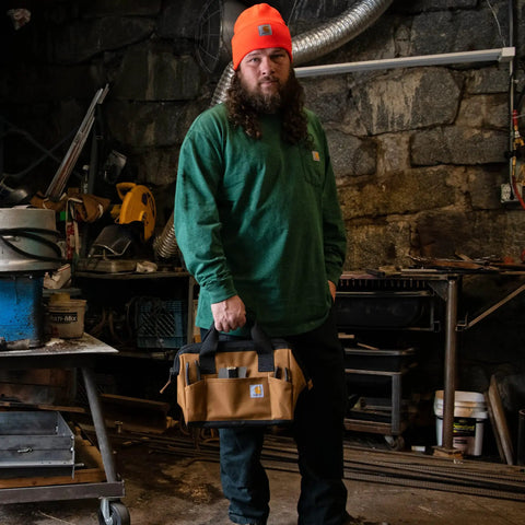 Man holding Beefy Duty Tool Bag With Large Zip Main Compartment, Six Exterior Pockets, Fifteen Interior Pockets And Loops, brown