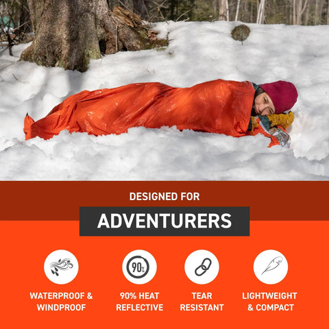 Person in snow using Ninety Percent Heat Reflective Emergency Bivvy With Survival Whistle And Paracord Drawstring, waterproof and windproof