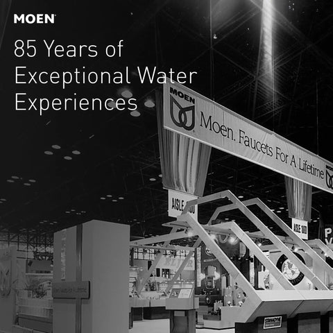 Moen exhibit at a trade show celebrating 85 years of exceptional water experiences, with banners and product displays.