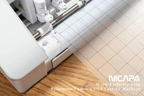 Nicapa 12x12 inch standard-grip cutting mat for Silhouette Cameo, shown beside the machine on a wooden desk.