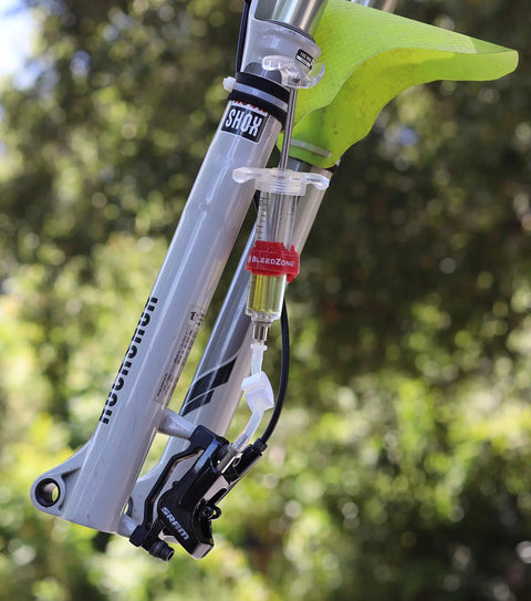 Hydraulic Bike Brake Bleed Kit For Avid, Formula, And Hayes Dominion With 2 Syringes, 2 Hose Fittings, DOT 5.1 Fluid, And Fasteners At Home Master Kit For Pro Grade Braking And Big Bucks in use with a mountain bike.