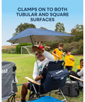 Person relaxing under Versa Brella Midnight Blue Outdoor Shade Umbrella With Heavy Duty Clamp on chair at park.