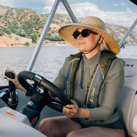 Person boating wearing USCG Approved Inflatable Life Jacket for Adults Go To Auto Or Manual Inflation, green color, nature backdrop