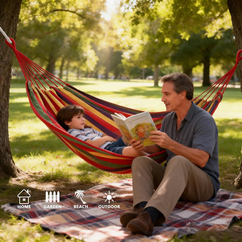 Man reading to child in a canvas hammock in a park setting, ideal for camping and outdoor relaxation