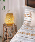 Dimmable Rattan Table Lamp With Boho Woven Shade And Bamboo Base on woven stand near bed