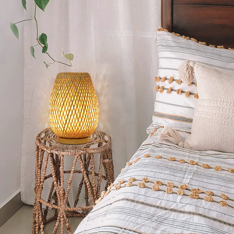 Dimmable Rattan Table Lamp With Boho Woven Shade And Bamboo Base on woven stand near bed