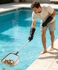 A man using Kick Some Serious Grime With These Xl 14 Inch Latex Chemical Resistant Gloves Heavy Duty Rubber Kitchen Gear to clean leaves from a pool.