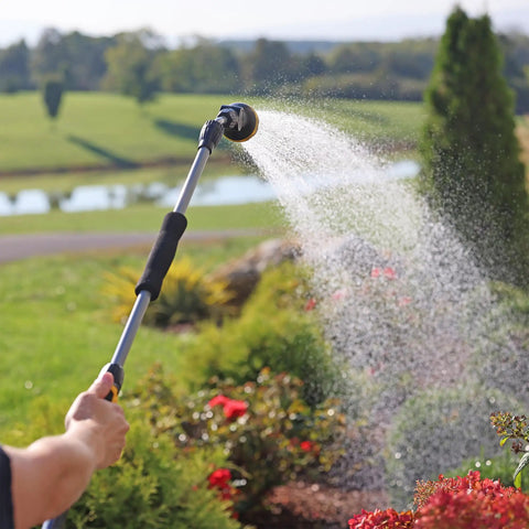 Person using RelaxGrip No Sweat Eight Pattern Pivoting Head Watering Wand with Quick Connect, extending water spray over garden plants