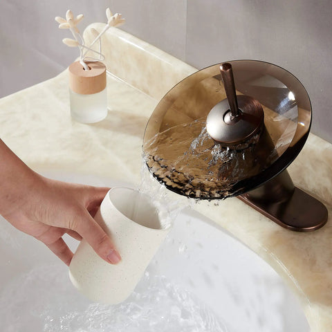 Oil Rubbed Bronze Waterfall Bathroom Sink Faucet With Brass Modern Circle Glass Disk Rinser pouring water into a white cup