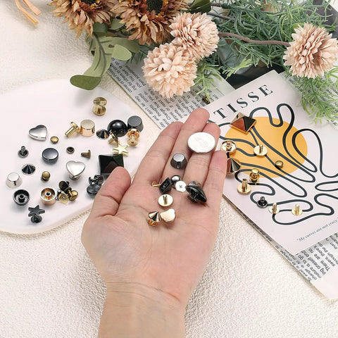 Level Up Your Look With These Top Shelf 30 Piece Heart Shaped Metal Stud Rivets 10Mm Screw Back Embellishments Ideal For Leather Gear Bags And Clothing DIY Projects Silver, assorted rivets in hand.