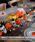 Table setup featuring Dripping Black Flameless Tea Lights 24 Pack With Warm White Flickering LED Candles For Halloween Decor Safe Battery Operated Party Pumpkins Haunted Home Gothic Vibe Spooky Easy Setup No Flame amid skulls and pumpkins.
