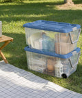 2 Pack 160 Quart Heavy Duty Rolling Storage Bins With Clear Transparent Walls And Tough Latching Lids For Smooth Glide Action outdoors stacked with household items.