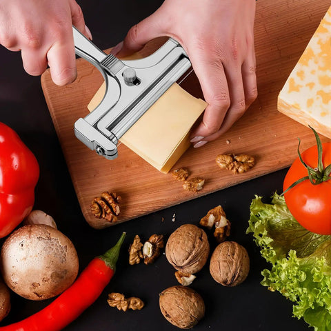 Built Tough Adjustable Cheese Slicer With Sharp Wire Cutter And Super Clutch Mini Silicone Tongs slicing cheese on a wooden board.
