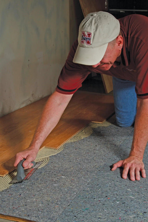 Pro Grade Flooring Underlayment Roll For Laminate Wood And Tile Sound Dampening Padding being installed by a man on the floor.