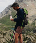 Hiker using Multifunctional Outdoor Hiking Compass With Scale And Luminous Mirror For Camping while trekking in mountains.