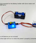 Front view: blue servo tester board with knob and LED, 4‑AA battery holder, FS90R micro servo